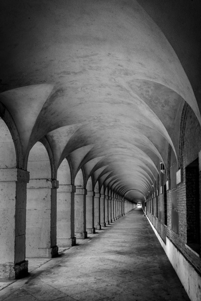 Explore this empty, eerie black and white arched hallway indoors.